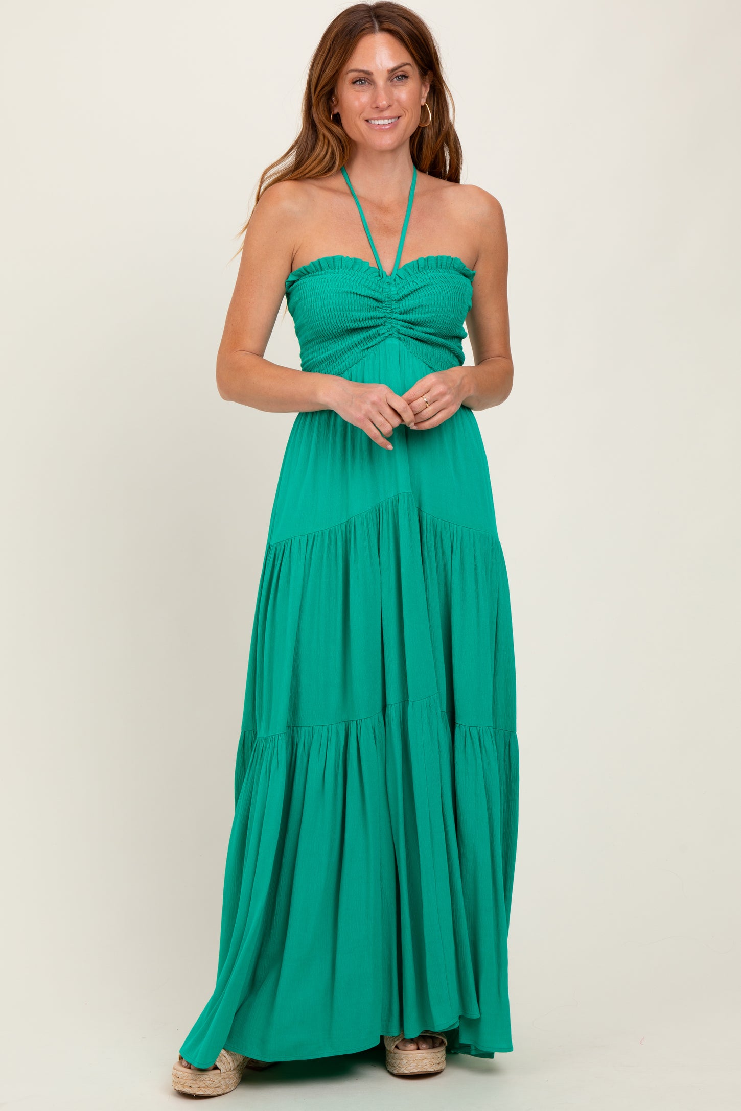 woman wearing a green halter neck maxi dress with a smocked bodice and tiered skirt