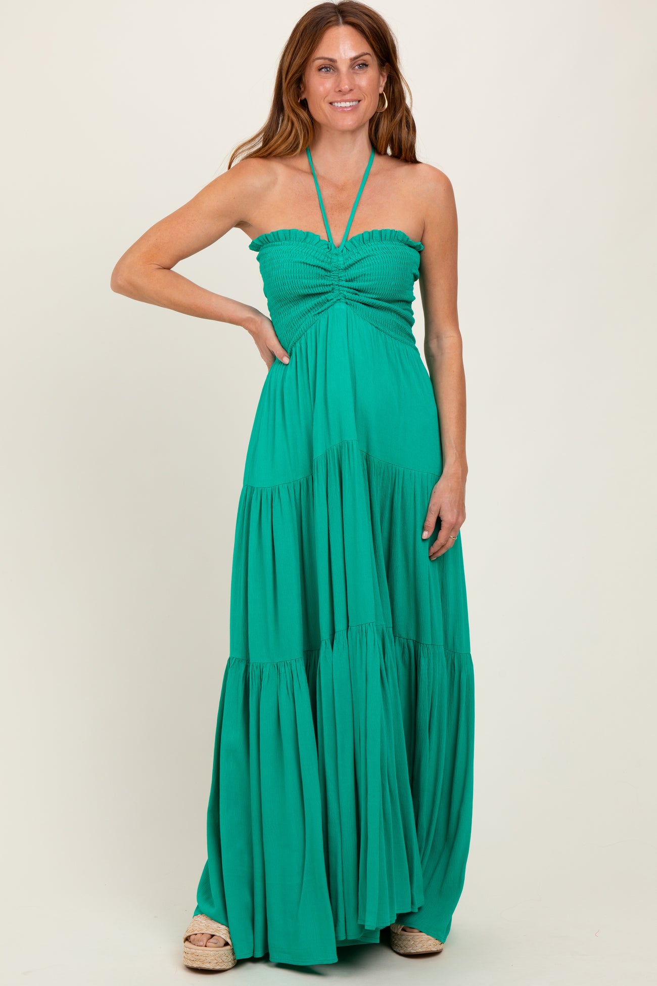 woman wearing a green halter maxi dress with smocked bodice and tiered skirt