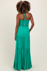 woman wearing a green maternity maxi dress with a smocked bodice and tiered skirt, showing off her baby bump from the back