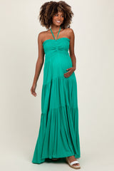 woman wearing a green halter neck maternity maxi dress and holding her baby bump