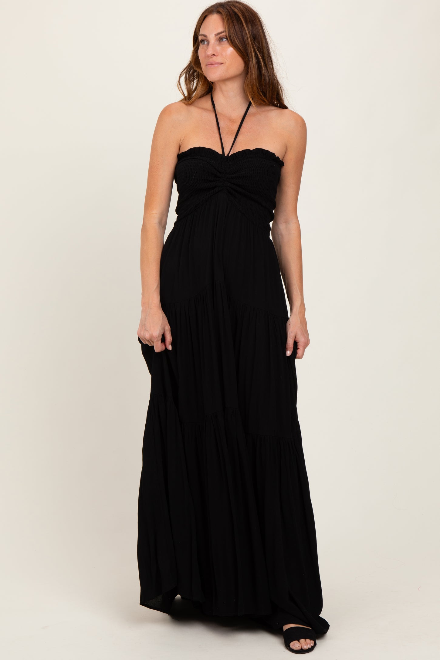 woman wearing a black strapless maxi dress with a smocked bodice and tiered skirt.