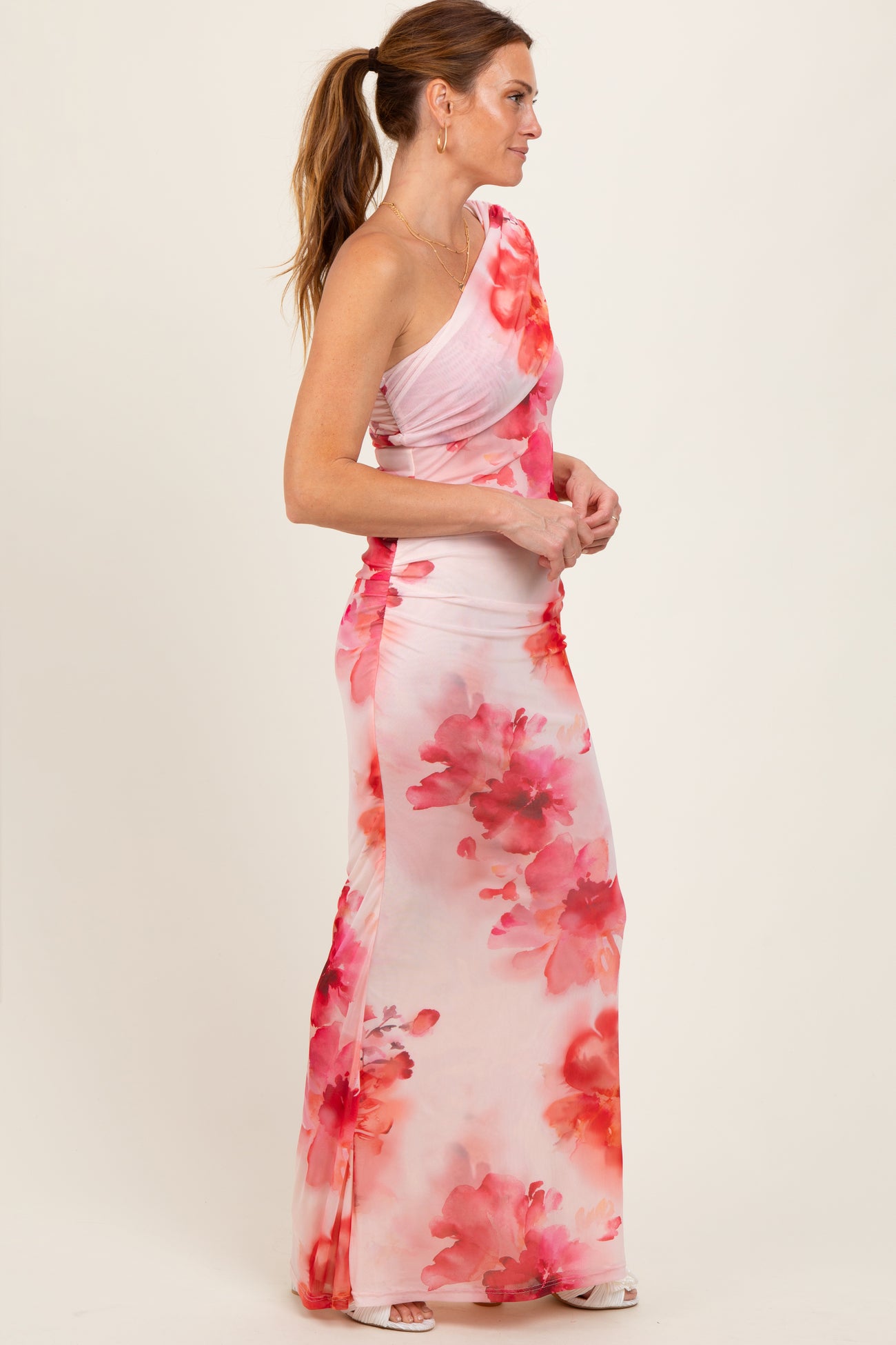 woman wearing a one-shoulder pink floral maxi dress with a ruched design