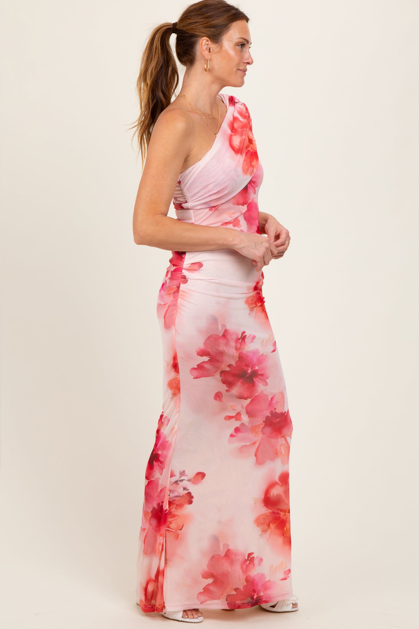 woman wearing a one-shoulder pink floral maxi dress with a ruched design