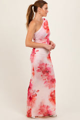 woman wearing a one-shoulder pink floral maxi dress with a ruched design