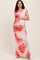 woman wearing a floral print one-shoulder maternity dress and holding her baby bump