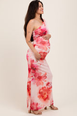 woman wearing a pink floral one-shoulder maternity dress and holding her baby bump