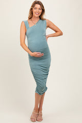 woman wearing a teal maternity dress with ruching details and holding her baby bump