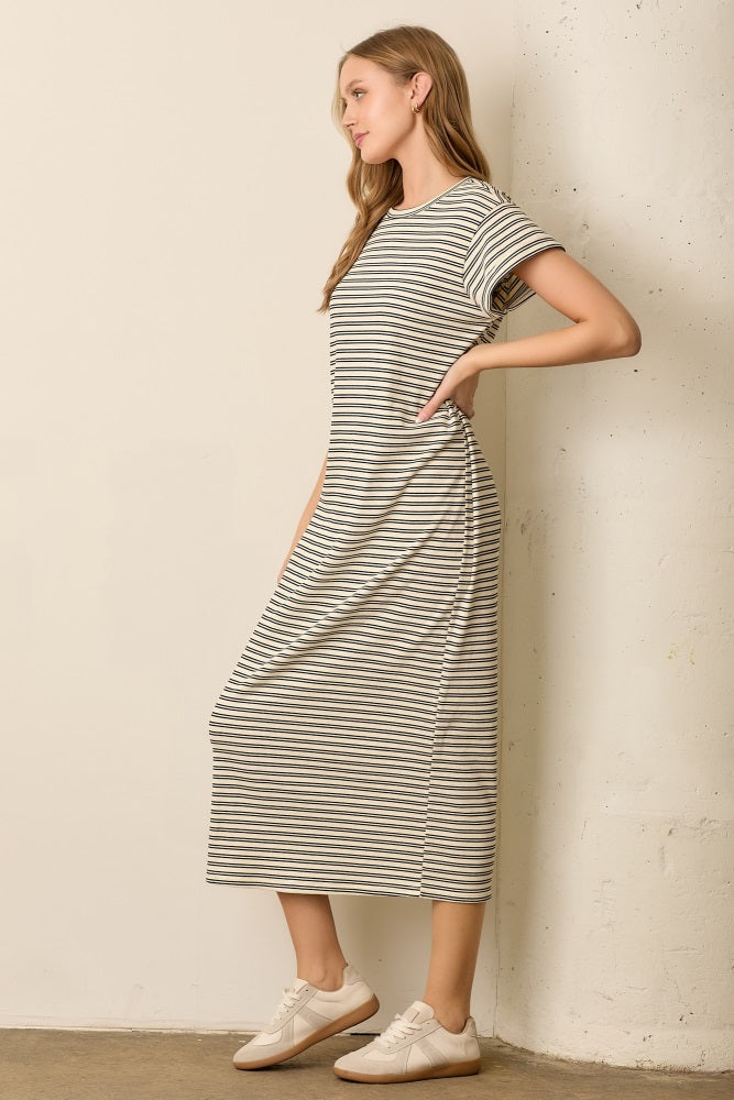woman wearing a striped midi t-shirt dress with short sleeves and side pockets, styled with white sneakers