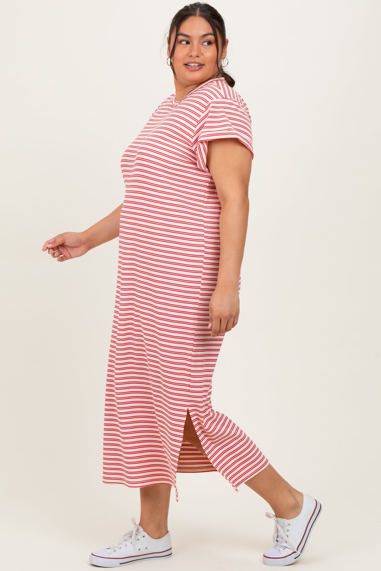 woman wearing a striped red and white maxi dress with short sleeves and a side slit, paired with white sneakers