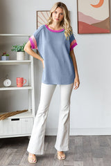 woman wearing a blue and white striped short sleeve top with pink accents and white flared pants