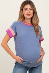 woman wearing a blue striped maternity top with pink and purple striped short sleeves, showing her baby bump