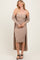woman wearing a ribbed beige midi dress with a matching long cardigan and black strappy heels