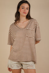 woman wearing a brown and cream striped oversized v-neck t-shirt with a front pocket and distressed white shorts