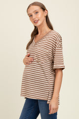 woman wearing a brown and beige striped maternity top and holding her baby bump