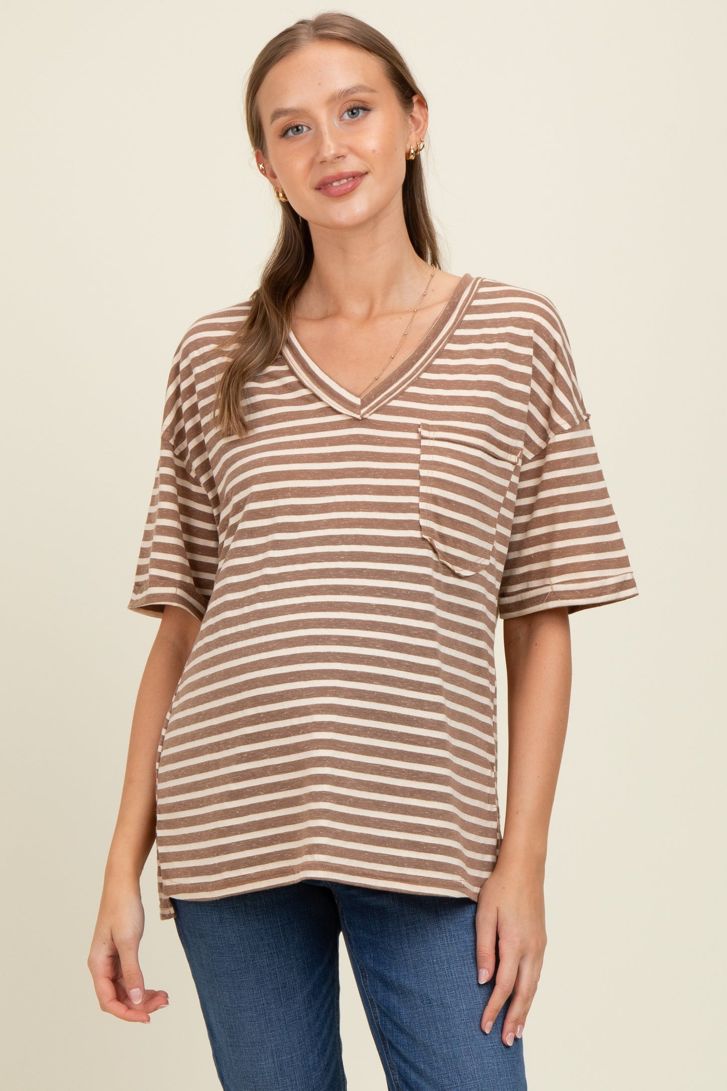 woman wearing a brown and cream striped maternity top with a v-neck and pocket, showing her baby bump