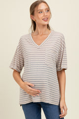 woman wearing a striped beige maternity t-shirt with a v-neck and pocket, holding her baby bump