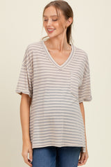 woman wearing a beige and gray striped maternity top with a pocket and v-neck, smiling, showcasing her baby bump