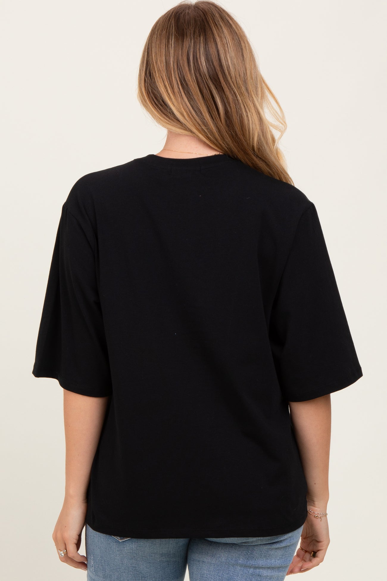 woman wearing a black oversized t-shirt seen from the back with short sleeves and a relaxed fit
