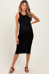 woman wearing a black ribbed maternity dress with a visible baby bump and standing in a relaxed pose