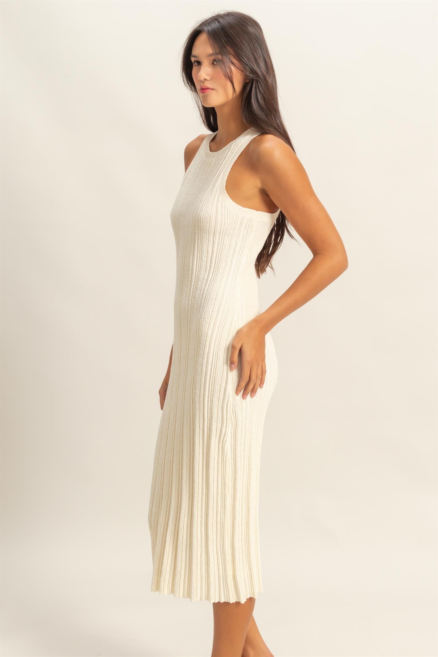 woman wearing a cream ribbed knit long dress with a fitted silhouette and sleeveless design