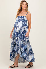 woman wearing a navy and white floral print maternity maxi dress with pockets and adjustable straps, showing her baby bump