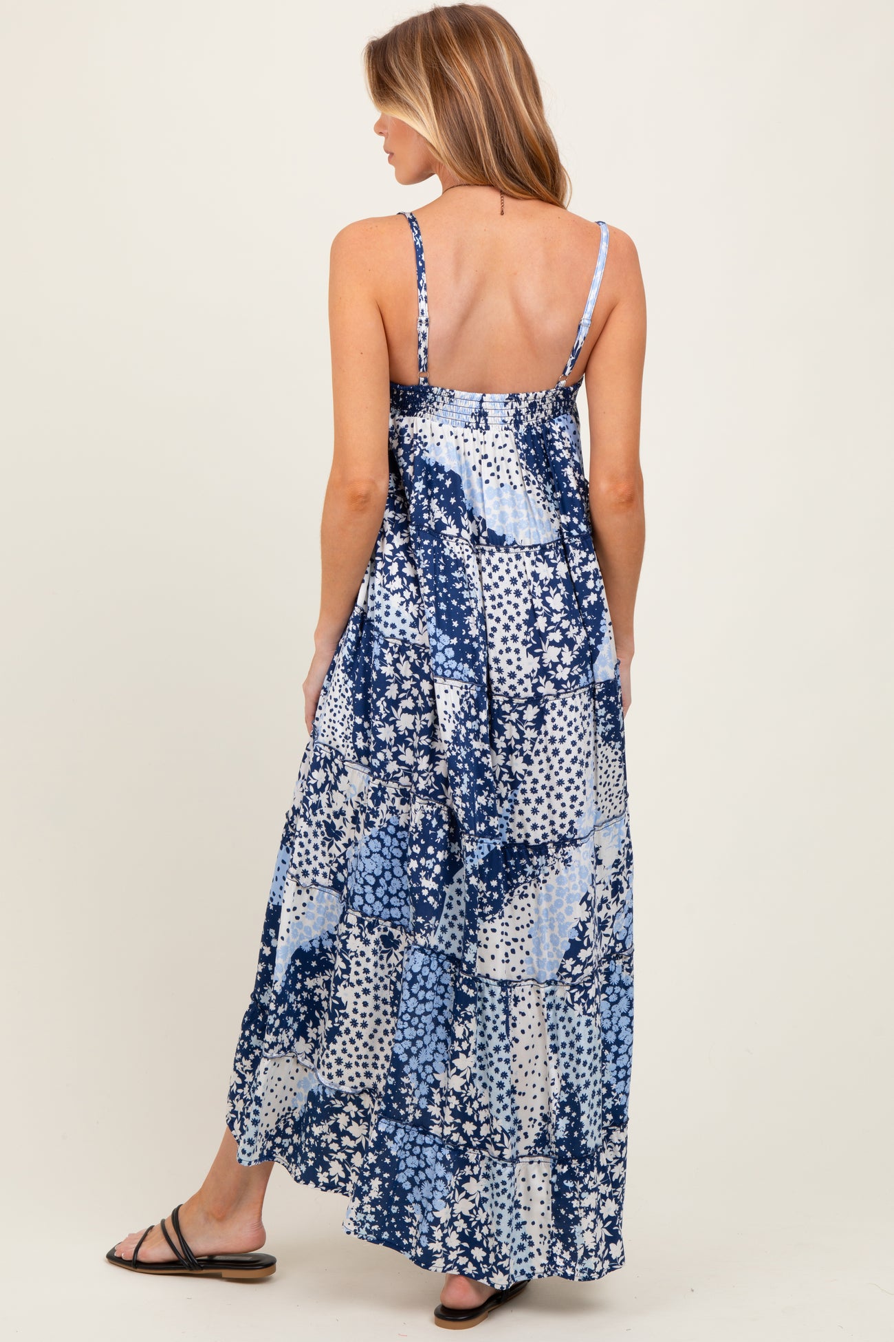 woman wearing a blue floral maternity maxi dress with adjustable straps, showing a baby bump from the back