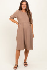 woman wearing a taupe maternity dress with short puff sleeves and a fitted bodice, showing her baby bump