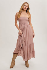 woman wearing a strapless blush pink maxi dress with smocked bodice and tiered skirt, holding a matching shawl
