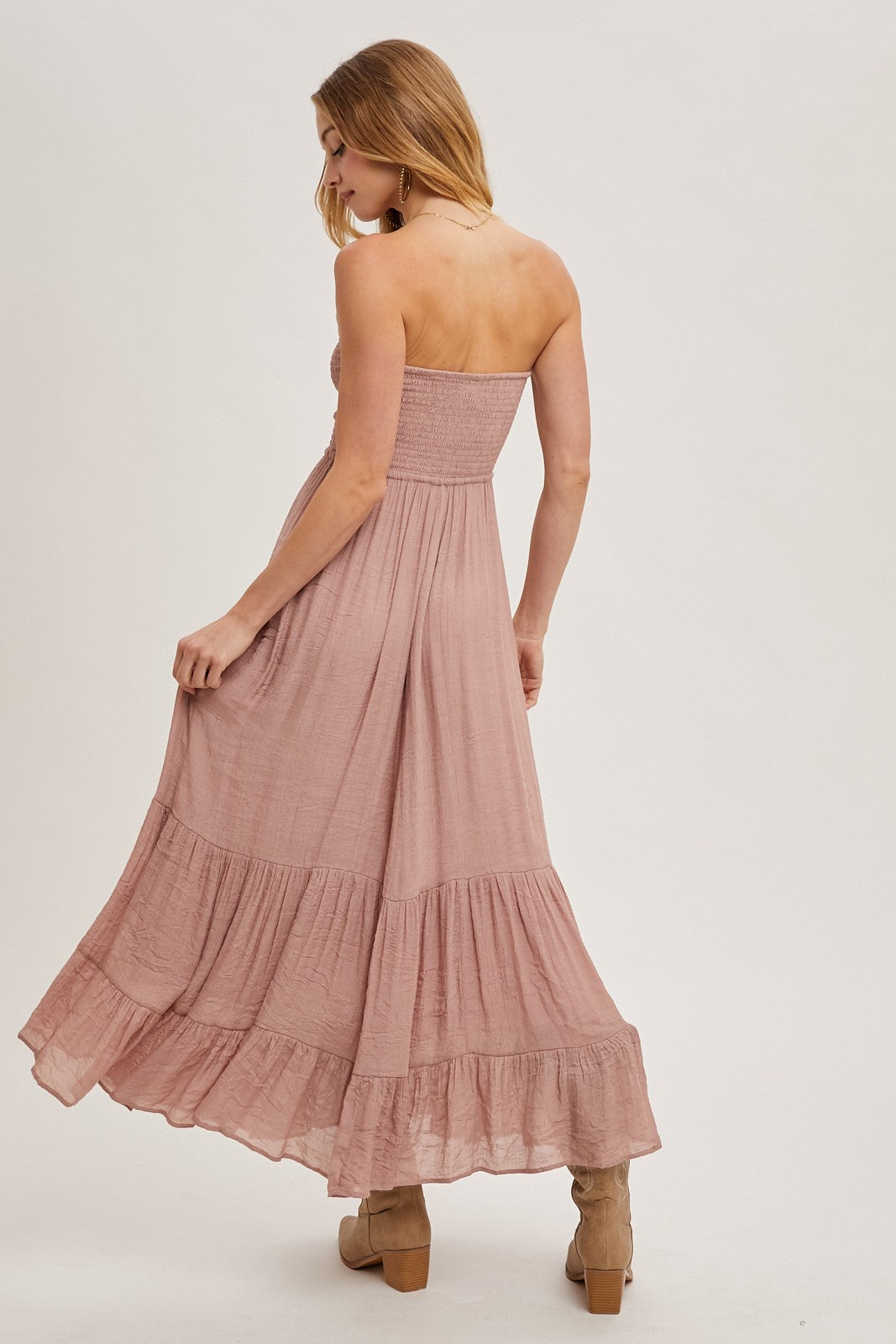 woman wearing a dusty pink strapless maxi dress with smocked bodice and tiered skirt