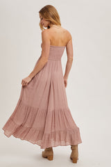 woman wearing a dusty pink strapless maxi dress with smocked bodice and tiered skirt