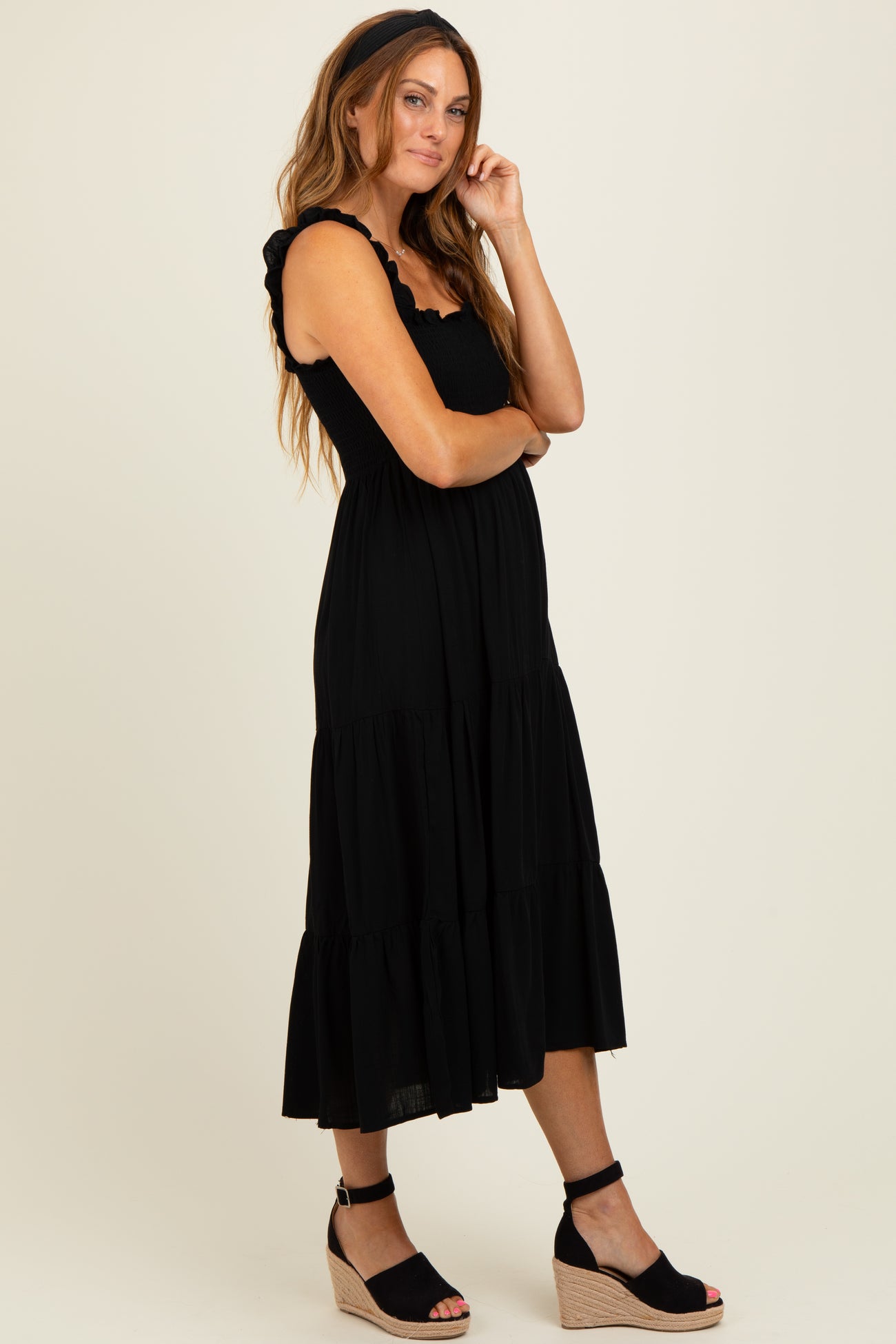 woman wearing a black tiered maxi dress with ruffle straps and black wedge sandals