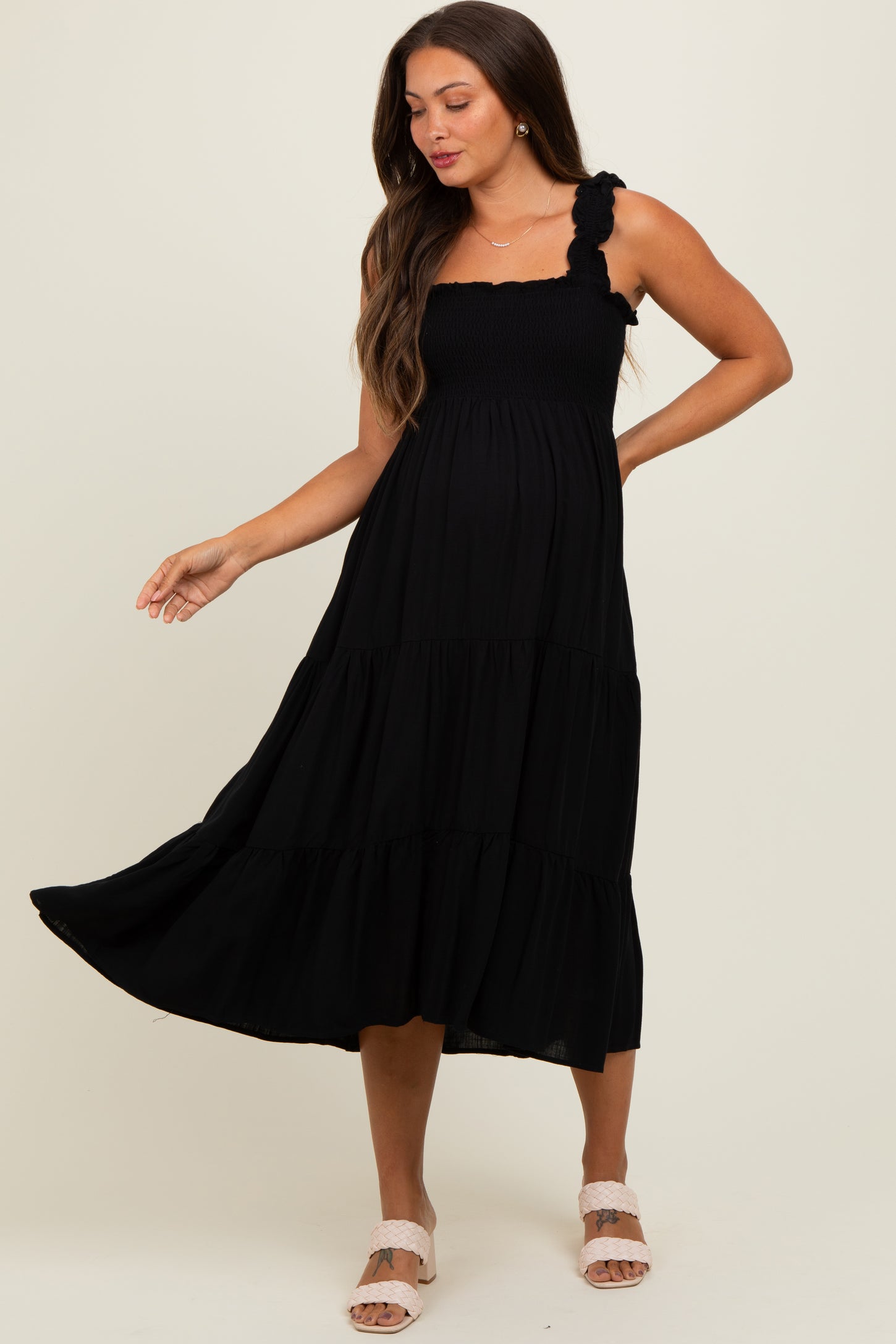 woman wearing a black maternity midi dress with smocked bodice and ruffled straps, showing her baby bump