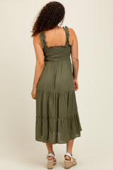 woman wearing an olive green maternity dress with ruffled straps and tiered skirt, showing her baby bump from behind