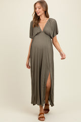 woman wearing an olive green short sleeve maternity maxi dress with a deep v-neck and a side slit, showing her baby bump
