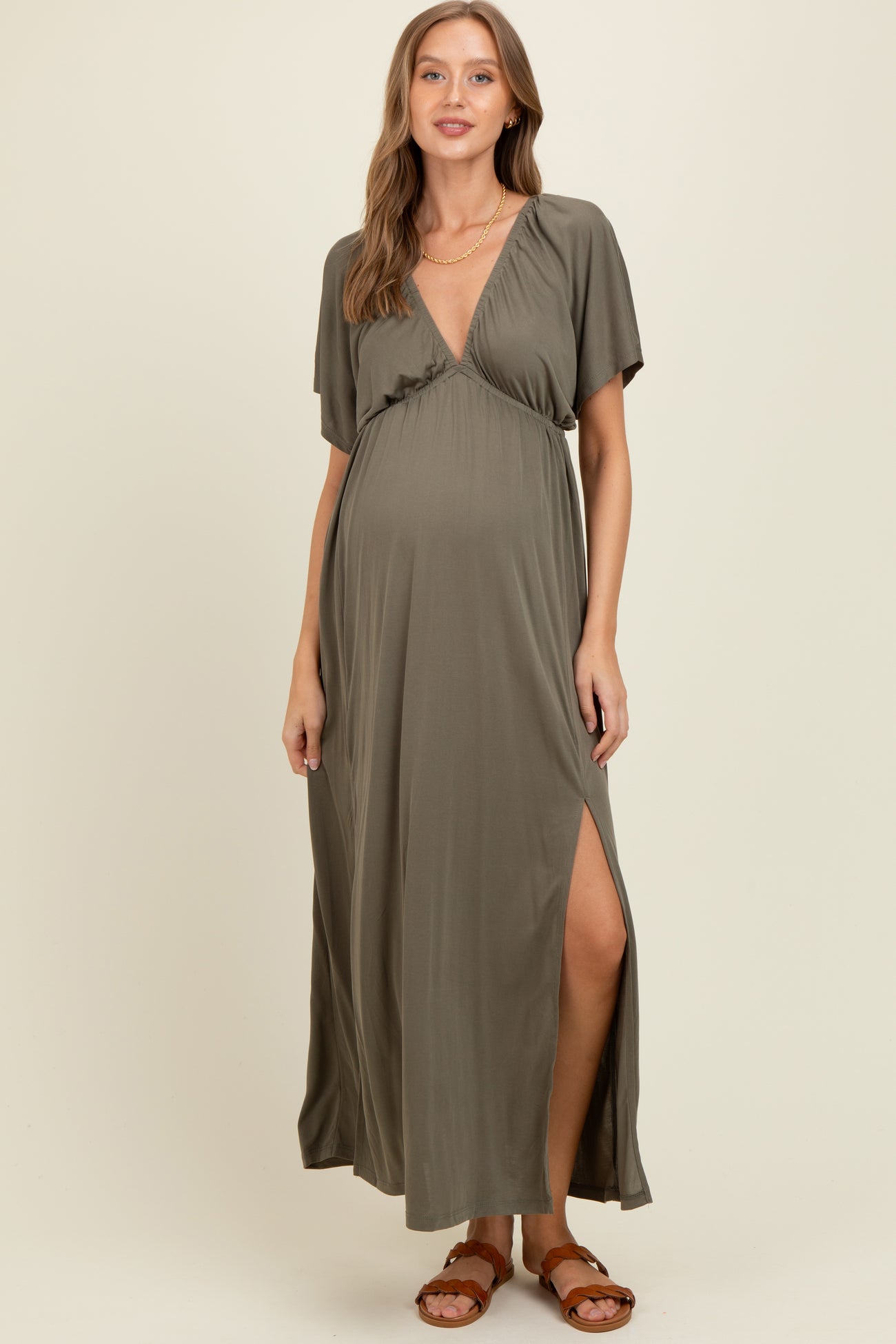 woman wearing a dark olive green maternity maxi dress with a wrap design and side slit, showing her baby bump