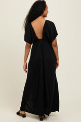 woman wearing a black maxi dress with a deep open back and short sleeves, shown from the back