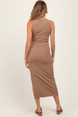 woman wearing a fitted ribbed maternity midi dress in light brown, seen from the back with no visible baby bump