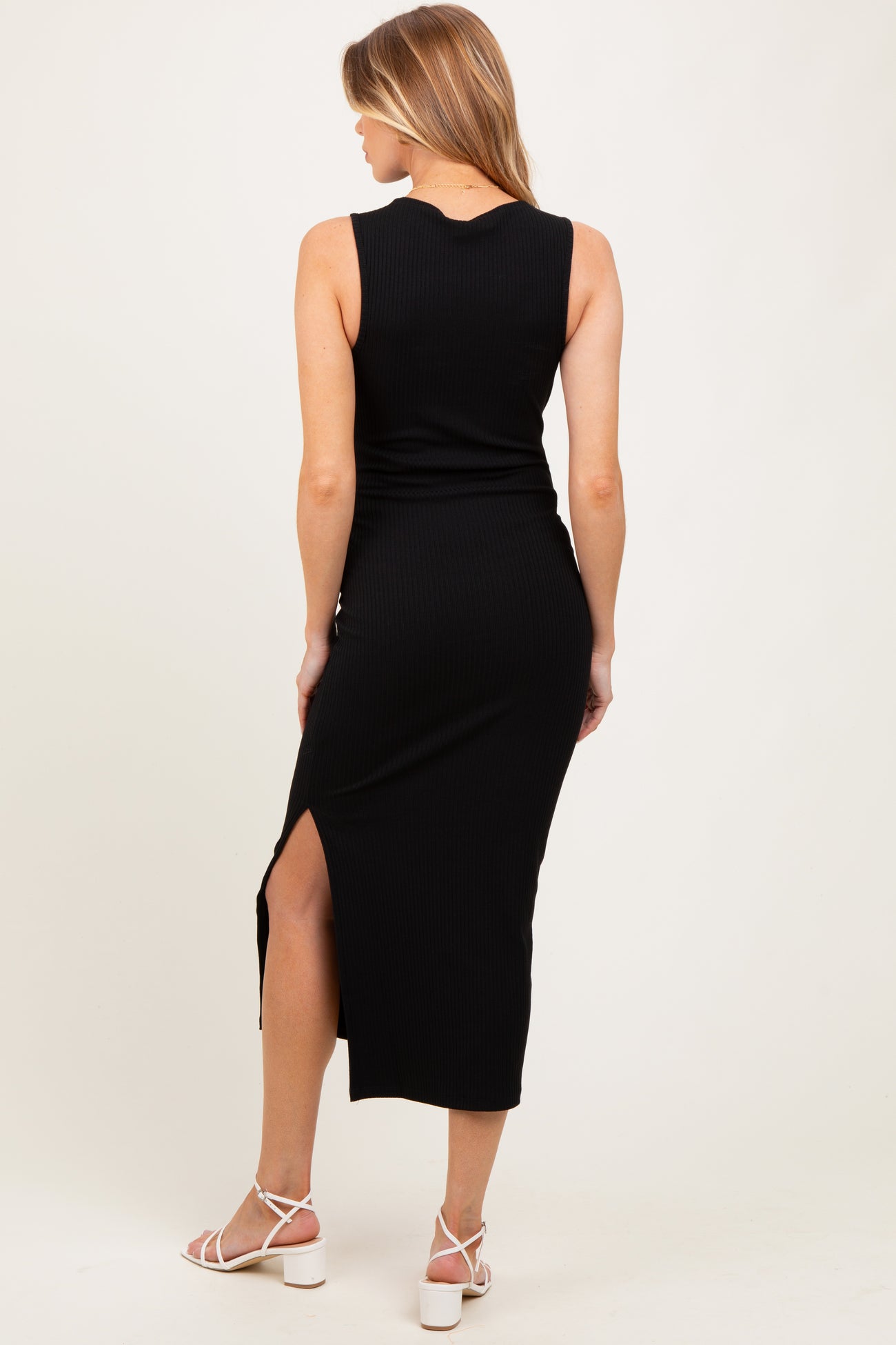 woman wearing a black ribbed maternity maxi dress with a side slit, showing the back view