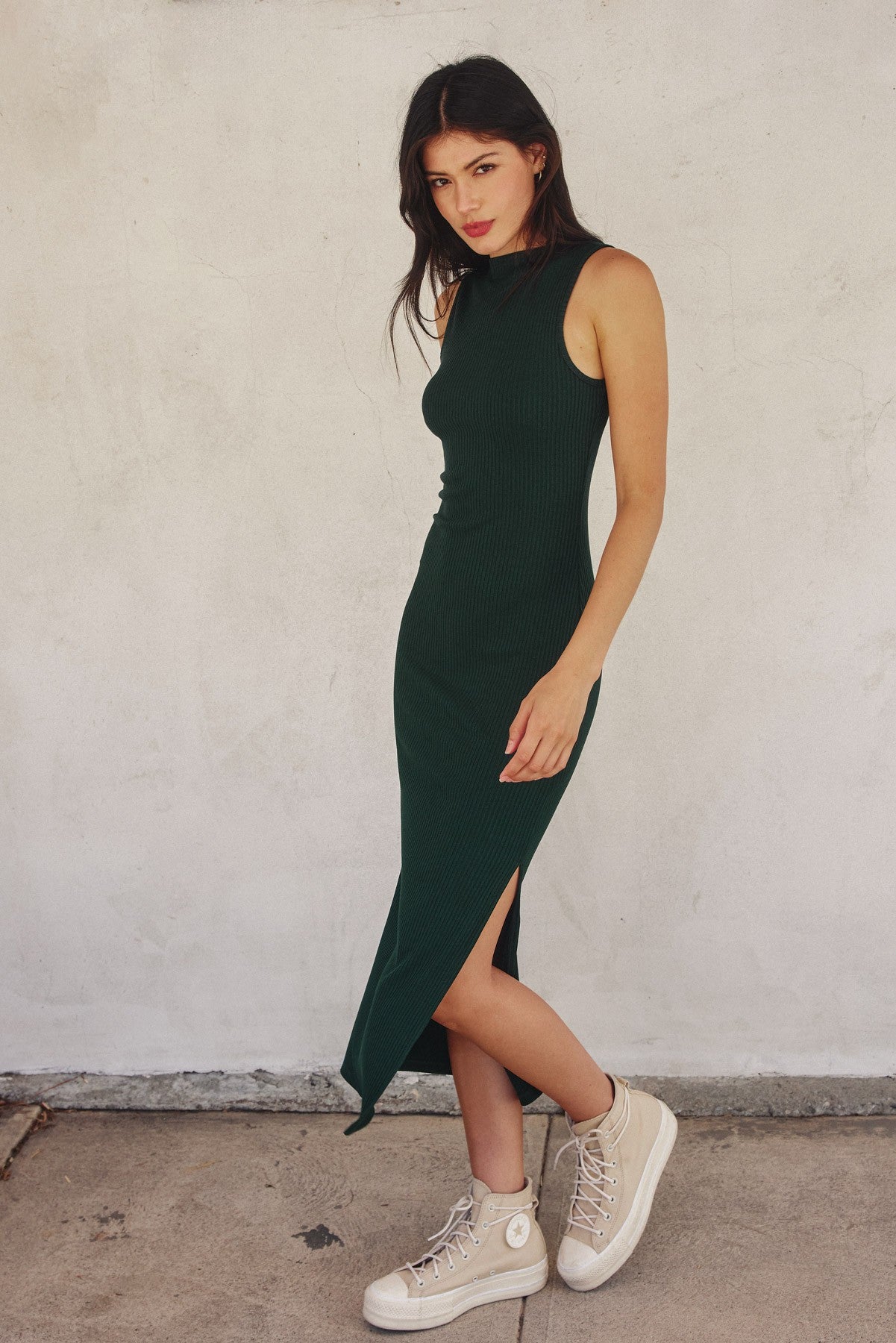 woman wearing a dark green ribbed midi dress with a side slit and beige platform sneakers