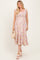 woman wearing a floral maternity maxi dress with ruffled straps and a tiered skirt, holding a woven bag