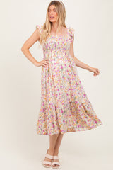 woman wearing a floral print maternity dress with ruffle sleeves and a flowy skirt, standing with one hand on her hip