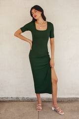 woman wearing a dark green ribbed midi dress with short sleeves and a side slit, posing against a neutral background