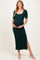 woman wearing a dark green ribbed maternity dress with short sleeves and a side slit, holding her baby bump