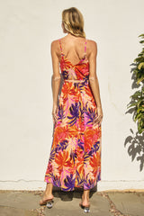 woman wearing a vibrant floral maxi dress with a tie waist, showcasing a colorful tropical print and spaghetti straps