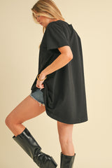 woman wearing an oversized black t-shirt with side slits, paired with denim shorts and tall black boots