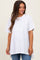 woman wearing a white oversized maternity tee with a high-low hem and smiling while standing against a neutral background