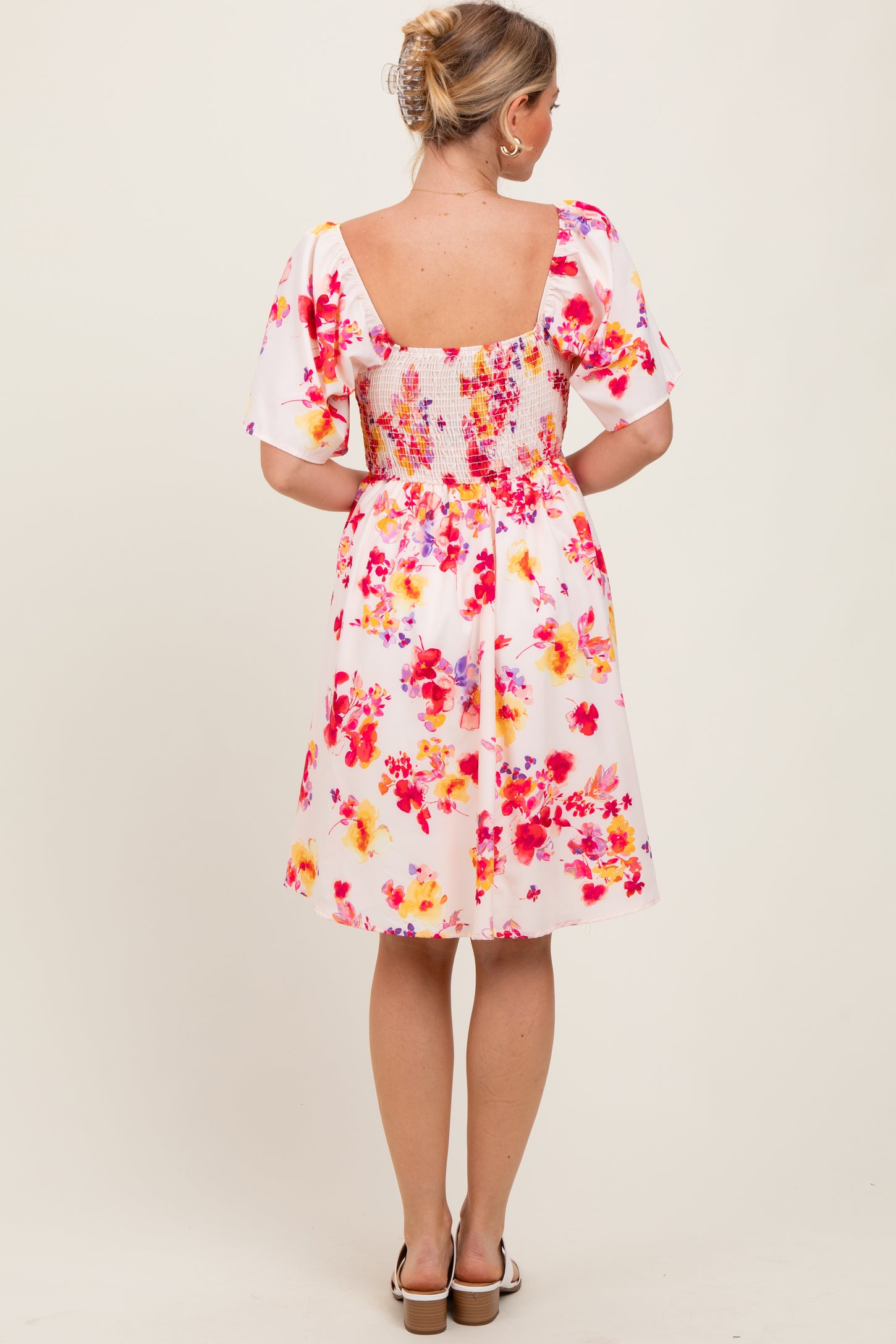 woman wearing a floral print short dress with puff sleeves and a smocked back detail