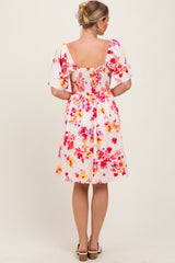 woman wearing a floral print short dress with puff sleeves and a smocked back detail