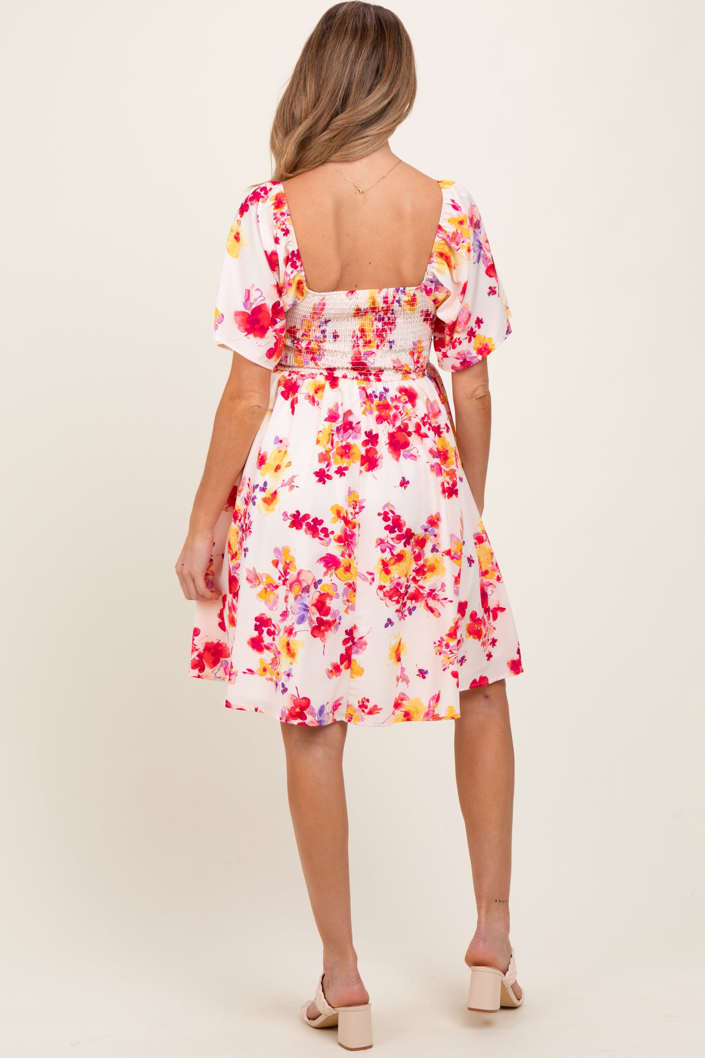 woman wearing a floral print maternity dress with puff sleeves and a smocked back, showing a baby bump