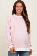 woman wearing a light pink striped maternity sweatshirt with white cuffs and a baby bump visible